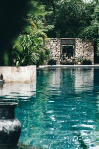 a swimming pool with a stone wall and blue water at Hotel Bardo - Adults Only in Tulum