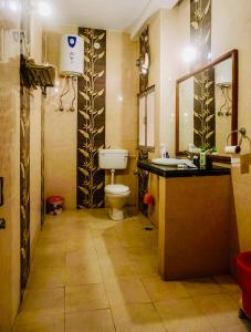 a bathroom with a toilet and a sink and a mirror at The Avantika Hotel & Woodland Restaurant in Gorakhpur