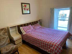 um quarto com uma cama com um cobertor xadrez e uma janela em Kickham Street Budget Accommodation em Carrick-on-Suir