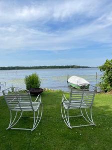 two benches sitting on the grass near a body of water at Haus am See in Schwielowsee
