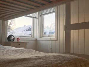 een slaapkamer met een bed en een raam met sneeuw bij Koselig leilighet med fantastisk utsikt in Tromsø