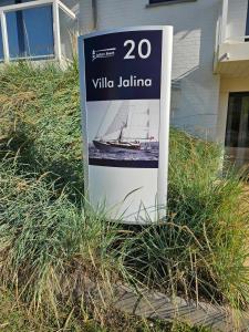 a sign sitting in the grass in front of a house at Sailors Beach VI Villa Jalina verwarmd zwembad in het hoogseizoen in Nieuwpoort