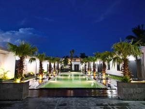 a swimming pool at night with palm trees at Heddin Homestay in Ben Tre