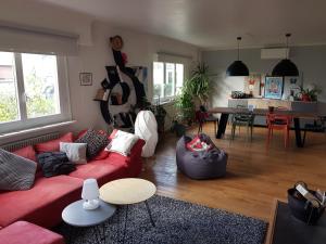 uma sala de estar com um sofá vermelho e uma mesa em Joli appartement calme et spacieux, proche Strasbourg em Duppigheim
