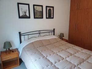 una camera da letto con un grande letto bianco e immagini appese al muro di Comfy and Izzy apartment a Karlovasi