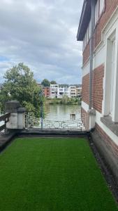 une cour d'herbe verte à côté d'un bâtiment dans l'établissement Studio vue sur Meuse, à Namur
