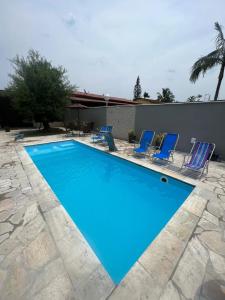 a large blue swimming pool with blue chairs at Casa para alugar em Bertioga - Piscina, Wifi e Churrasqueira in Bertioga