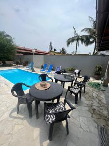 a patio with tables and chairs next to a pool at Casa para alugar em Bertioga - Piscina, Wifi e Churrasqueira in Bertioga
