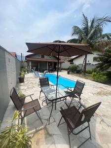 a patio with chairs and an umbrella and a pool at Casa para alugar em Bertioga - Piscina, Wifi e Churrasqueira in Bertioga +17 photos
