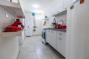 eine weiße Küche mit weißen Schränken und roten Geräten in der Unterkunft Encanto do Francês (4 minutos, a pé, da Praia) in Praia do Frances