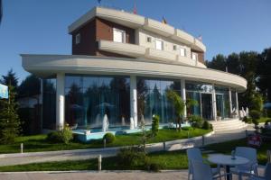 a building with a table and chairs in front of it at Apple Red Hotel in Fier