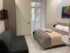 Residenza Suarez في نابولي: غرفة نوم بسرير وتلفزيون وأريكة