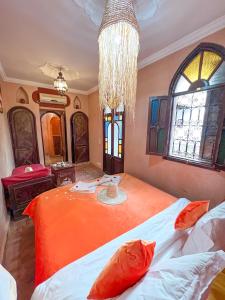 a bedroom with an orange bed with a chandelier at Riad Elli Marrakech in Marrakesh