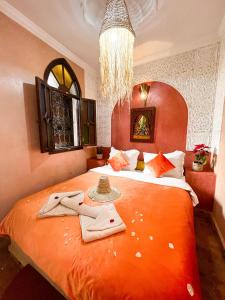a bedroom with a large orange bed with towels on it at Riad Elli Marrakech in Marrakesh