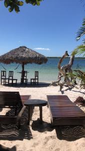una spiaggia con tavoli e sedie e un ombrellone di paglia di Villa Encantos do Paraíso 50mts da lagoa a Jijoca de Jericoacoara Altre 24 foto