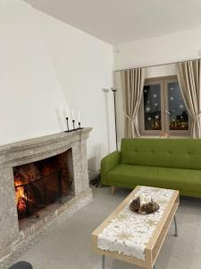 a living room with a green couch and a fireplace at LE CANONICHE NEL MATESE ALBERGO DIFFUSO in San Massimo