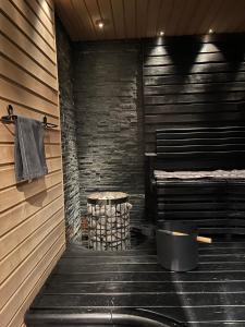 a sauna with a stone wall and a pot of wood at Villa Aurora View in Rovaniemi