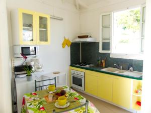 una pequeña cocina con armarios amarillos y una mesa en Les Colibris, en Sainte-Anne
