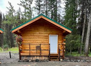 Cabaña de madera con puerta blanca y silla en Carlo Creek Cabins en McKinley Park