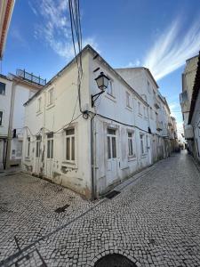 an old white building on a cobblestone street at Metamorphosis in Nazaré +10 photos