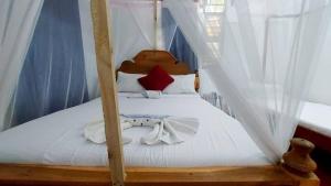 a bedroom with a canopy bed with white sheets at Jacob's Inn Jambiani in Jambiani