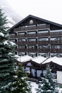 a large building with snow on the ground at Le Mirabeau Resort & Spa in Zermatt