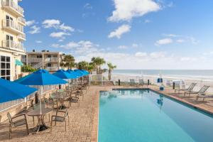 una piscina con mesas y sillas y la playa en SpringHill Suites by Marriott New Smyrna Beach en New Smyrna Beach