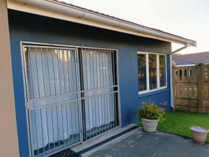 a blue house with a gate and a door at Blissful Stays in Richards Bay