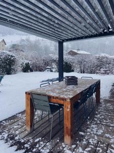 a wooden table with two chairs under a roof at Grand chalet à la montagne in Bourg-Saint-Maurice