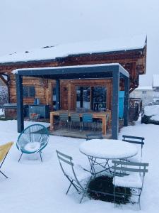 a table and chairs in the snow in front of a cabin at Grand chalet à la montagne in Bourg-Saint-Maurice