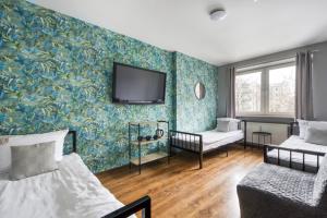 a room with two beds and a tv on a wall at Apartamenty Stara Praga - Wiatraczna in Warsaw