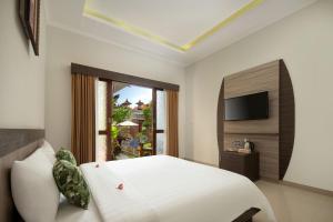a bedroom with a white bed and a television at Jineswari Kuta by Kamara in Kuta