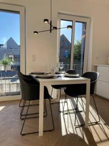 une table à manger blanche avec des chaises noires et un lustre dans l'établissement Stilvolles Ferinen-Apartment im Herzen von Xanten, à Xanten