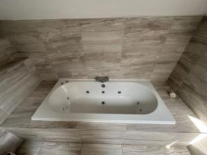 a bath tub in a bathroom with a stone wall at Jaw Dropping House with Private Indoor Pool and Hot Tub in Peover Superior