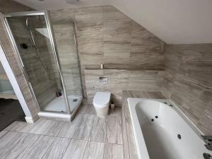 ein Bad mit einer Badewanne, einem WC und einer Dusche in der Unterkunft Jaw Dropping House with Private Indoor Pool and Hot Tub in Peover Superior