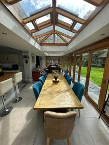 a conservatory with a wooden table and blue chairs at Jaw Dropping House with Private Indoor Pool and Hot Tub in Peover Superior