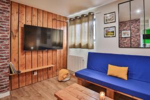 ein Wohnzimmer mit einem blauen Sofa und einem TV in der Unterkunft CHALET CAMPAGNE Les Belles Ouvrières in Clermont-Créans