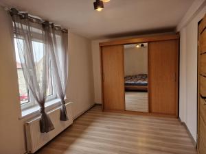 ein Schlafzimmer mit einer Tür mit einem Spiegel und einem Fenster in der Unterkunft Rodzinny apartament + siłownia in Bytom