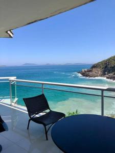 a chair sitting on a balcony overlooking the ocean at Lindo Flat praia deserta búzios in Armacao dos Buzios