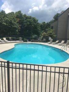 a large blue swimming pool with chairs and a fence at Comfy Condo With Amazing View of Gatlinburg and the Smokies in Gatlinburg