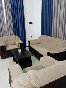 a living room with couches and a table and blue curtains at Dream Villa in Matara