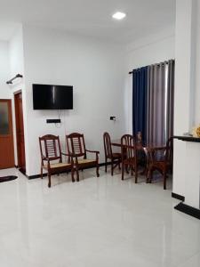 a living room with chairs and a table and a flat screen tv at Dream Villa in Matara