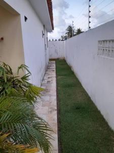 an alley with a white wall and grass next to it at Bela casa de Veraneio - faça sua reserva. in Lucena