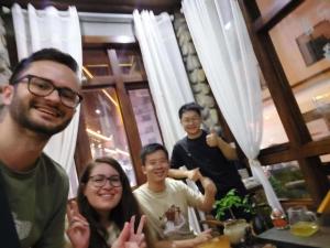 un grupo de personas sentadas en una mesa posando para una foto en Zhangjiajie Highlights Guesthouse en Zhangjiajie