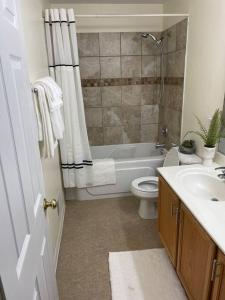 a bathroom with a tub and a toilet and a sink at Family home on fescue in Aurora