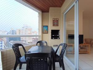 a balcony with a table and chairs and a window at Apê com churrasqueira guilhermina in Praia Grande