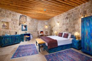 a bedroom with a bed and a stone wall at Cappadocia Pema Cave Hotel in Ortahisar