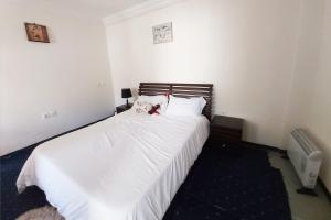 Un dormitorio con una cama blanca con dos animales de peluche. en Attractive 1 BR House in Bole Atlas en Addis Abeba