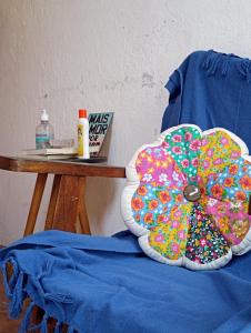 een kleurrijk kussen zittend op een stoel naast een tafel bij Tiwá Hostel - antigo DaSanta - CENTRO in Arraial d'Ajuda