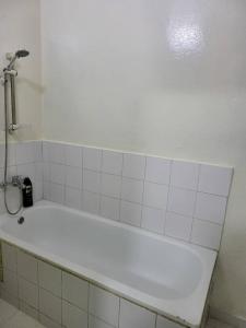 a white bath tub in a white tiled bathroom at Jado house 4 in Dakar